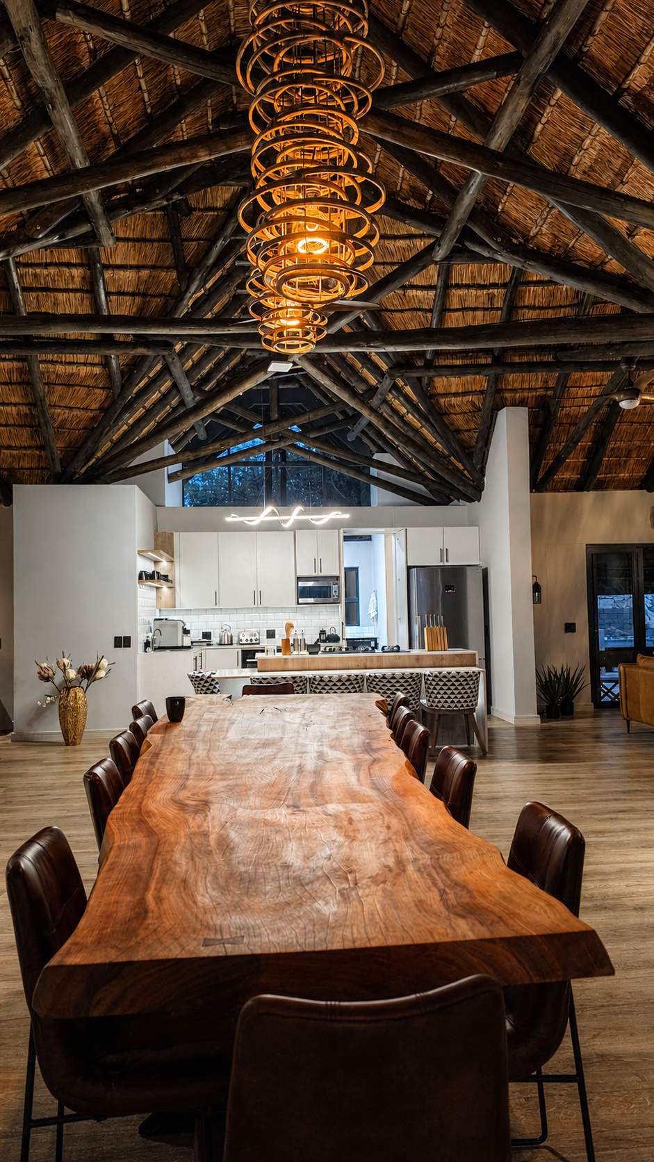 The live-edge dining table beneath the cathedral thatch and pendant lights.